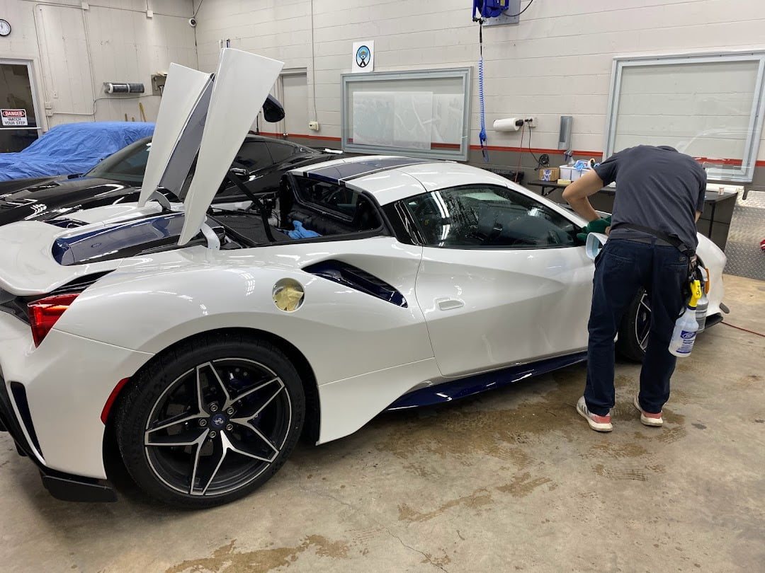 Installer fitting paint protection film on a white Ferrari
