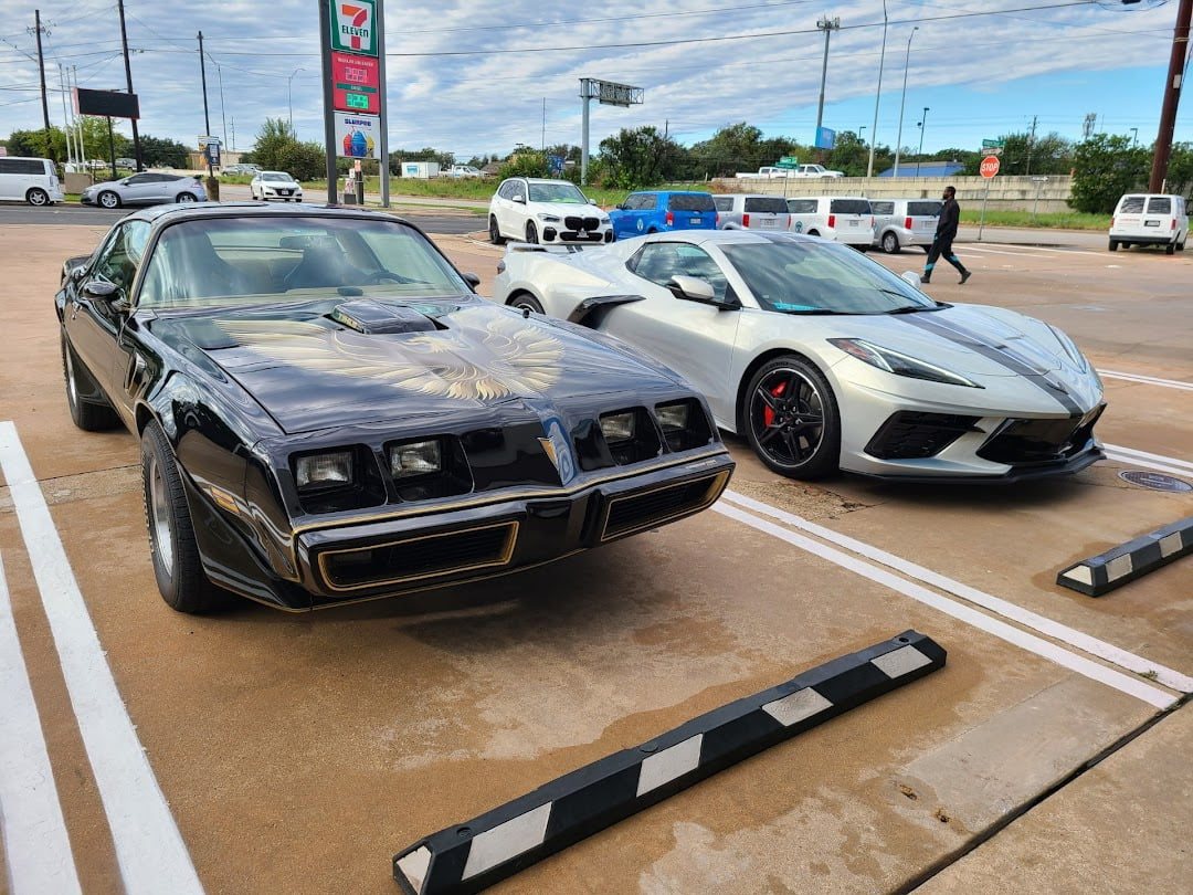 Black Trans Am beside a new Corvette